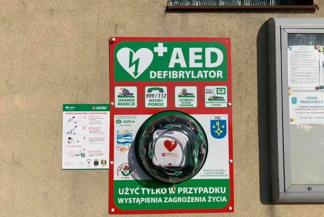 Oznakowany punkt pierwszej pomocy z defibrylatorem AED na ścianie