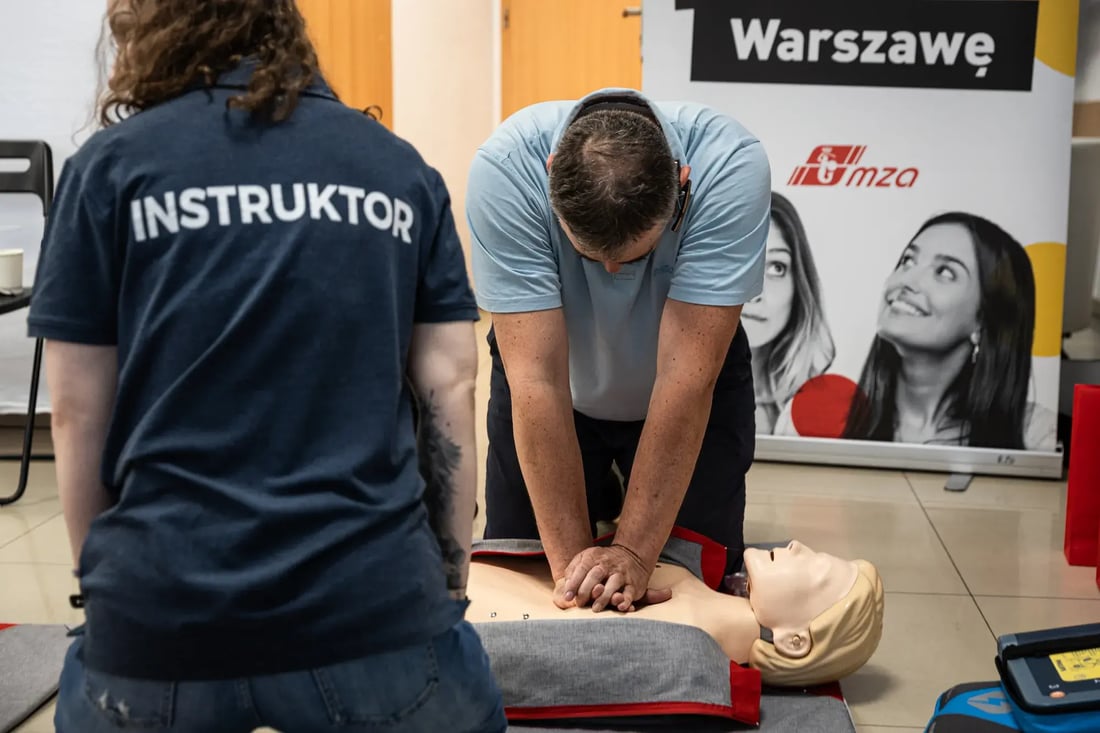 Kursant ćwiczy uciskanie klatki piersiowej na fantomie pod okiem instruktora